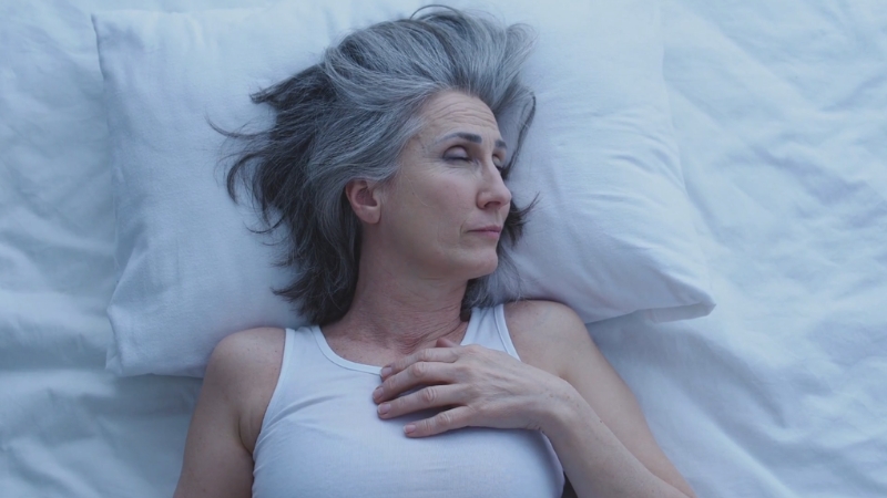 Žena leži na leđima na jastuku u krevetu