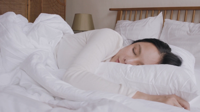 Žena leži na jastuku u krevetu