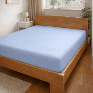 Čaršav sa gumom svetlo plave boje zategnut preko dušeka na drvenom krevetu u spavaćoj sobi