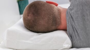 Muškarac leži na jastuku koji pravilno podržava vrat, što pokazuje kako anatomski jastuci pomažu kod bola u vratu