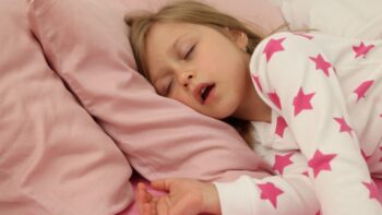 Devojčica spava otvorenih usta na jastuku, što može ukazivati na hrkanje tokom noći